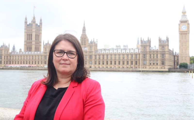 Rachel Hopkins MP in red jacket with Parliament in the background