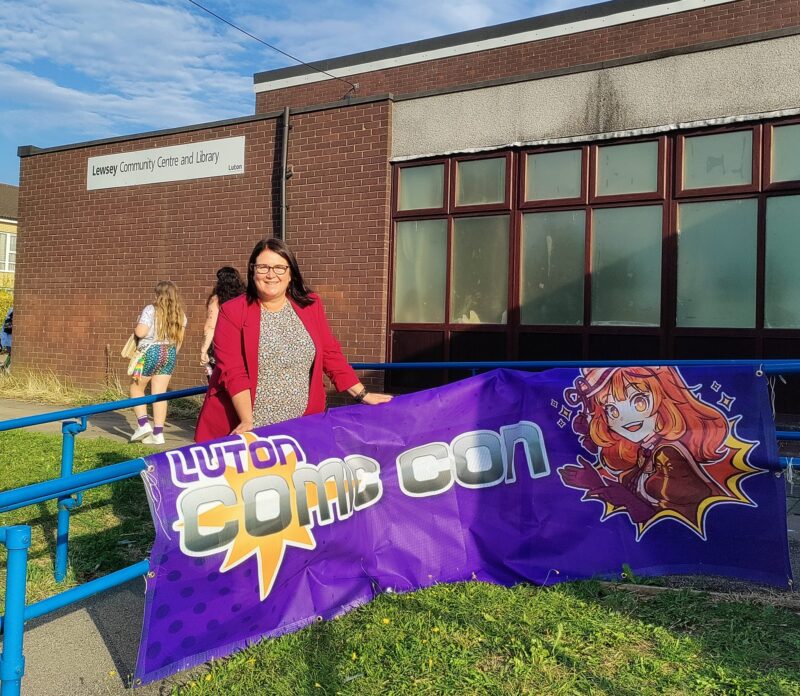 Rachel standing behind the Luton Comic Con sign